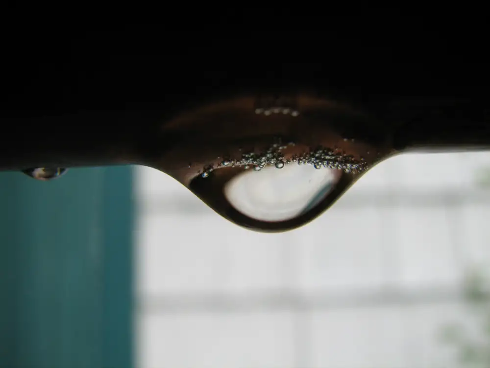 Gota de agua colgando de una tubería de cobre